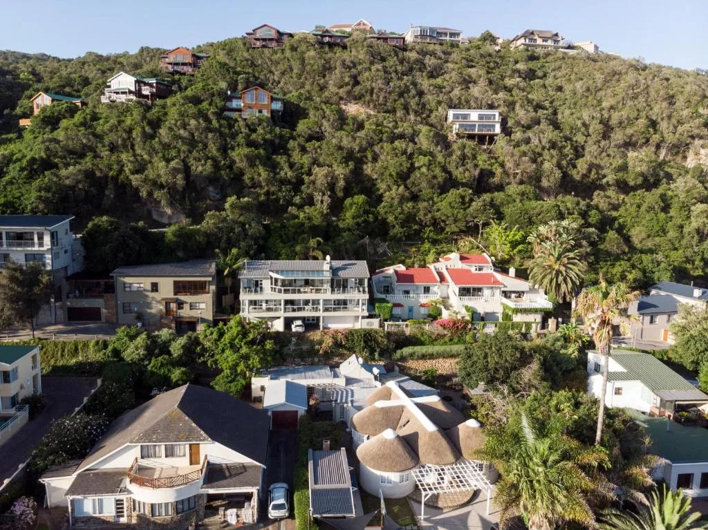 Aerial view of coastal property nestled among lush greenery and neighboring homes