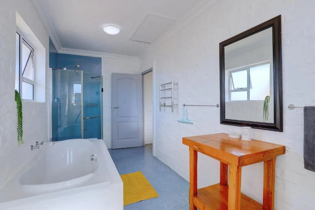 Modern bathroom with blue shower enclosure, white bathtub, wooden vanity