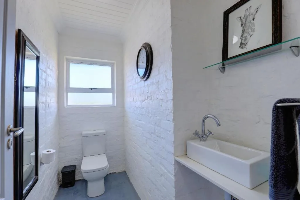 Clean modern bathroom with white brick walls, toilet, and vessel sink