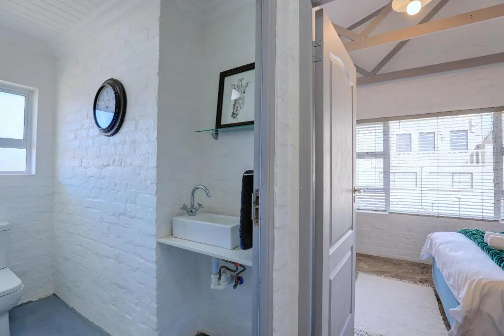 Bright white bathroom with basin sink, clock, and toilet visible