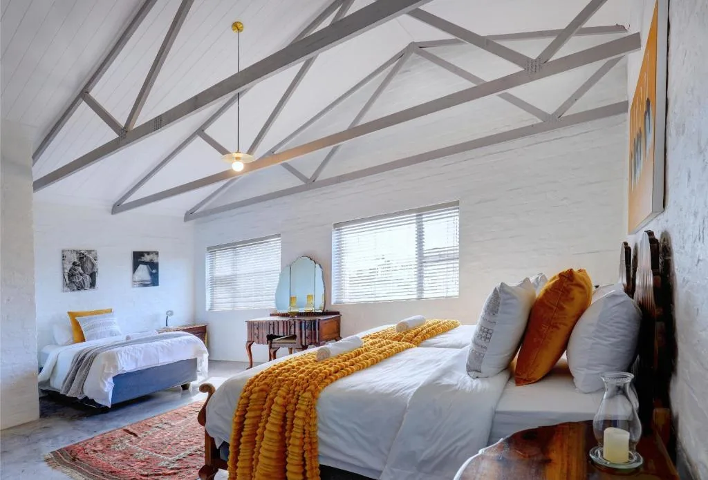 Spacious bedroom with exposed beam ceiling, two beds, golden accents