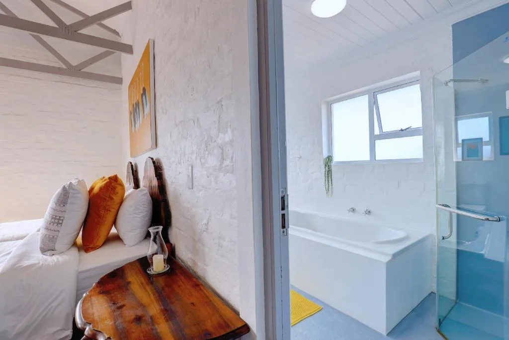 Bedroom with white bed, colorful pillows, and open bathroom door