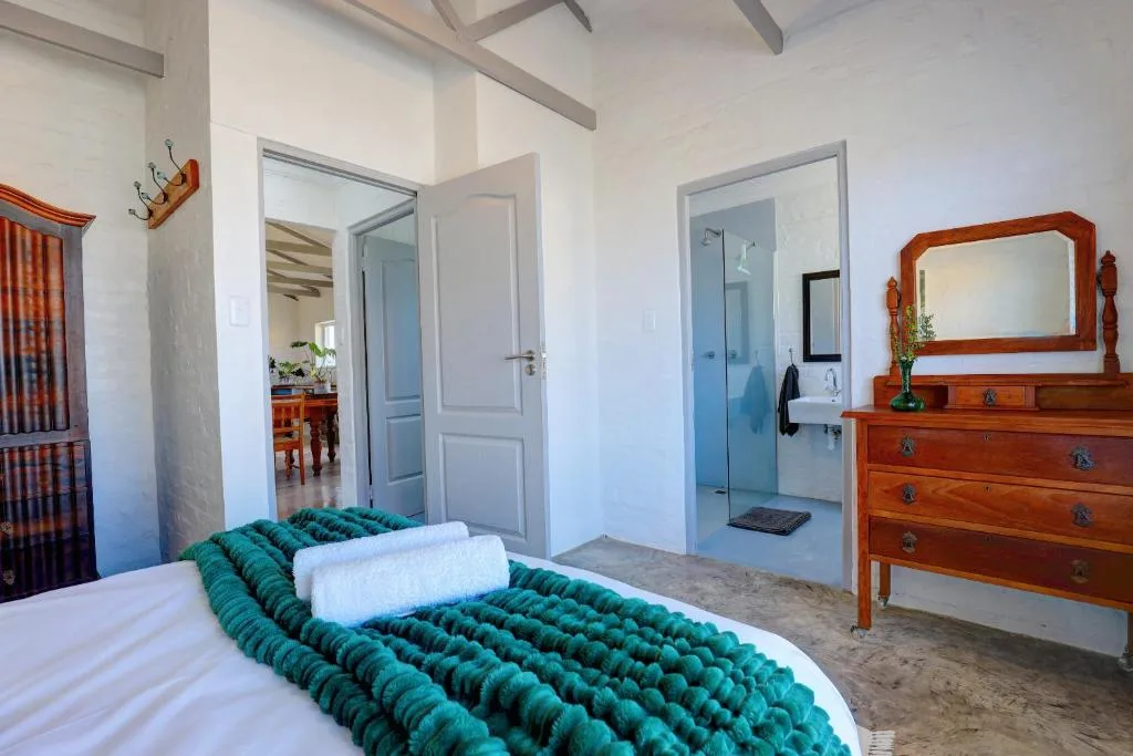 Spacious bedroom with bed, wooden dresser, and ensuite bathroom access