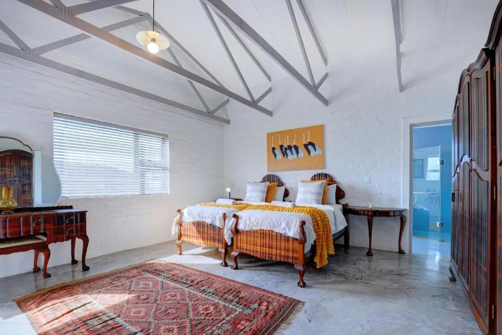 Spacious bedroom with high ceilings, twin beds, and bright natural light