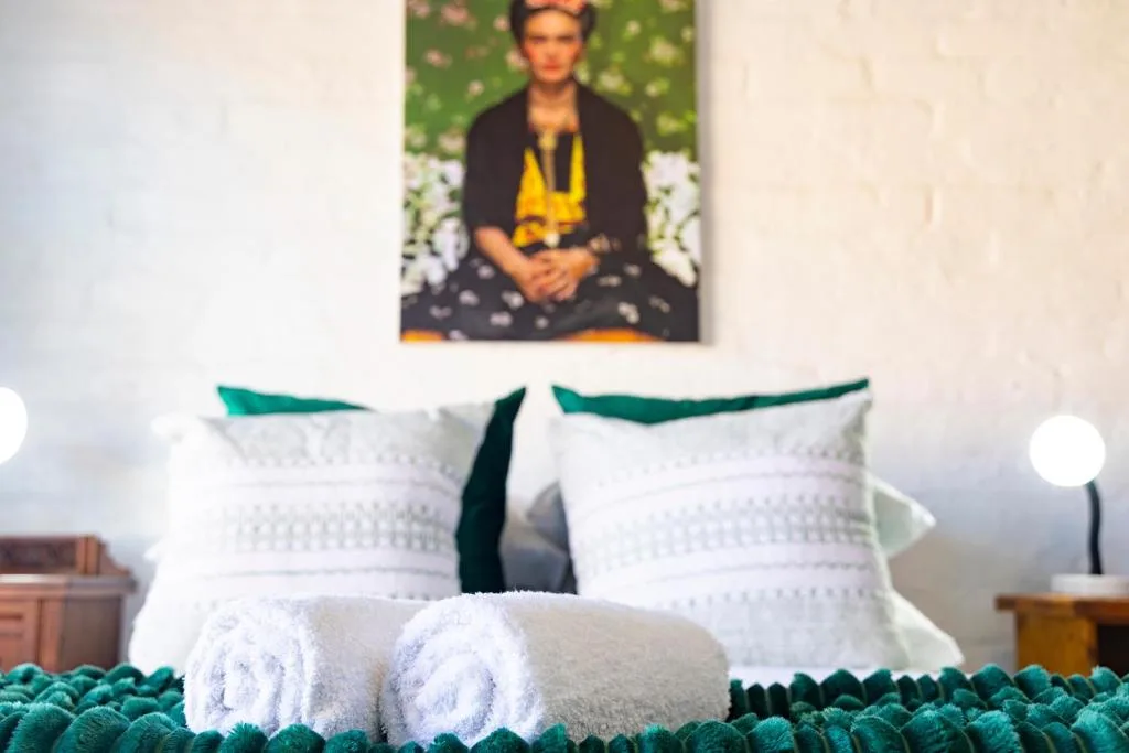 Bedroom with white pillows, teal accents, and framed artwork above bed