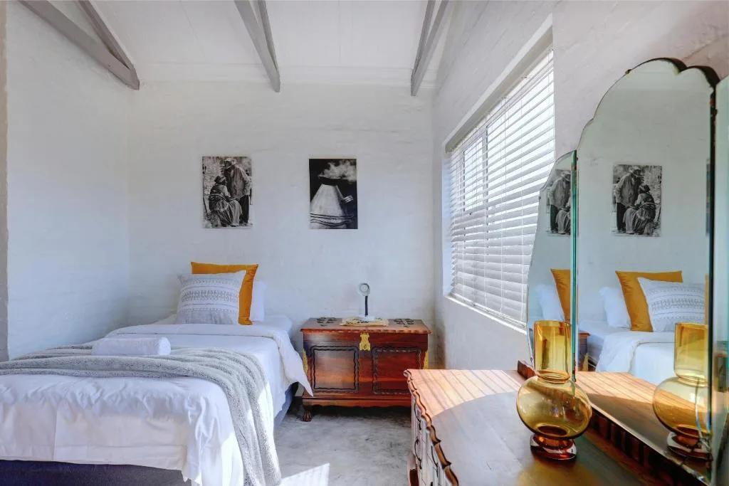 Bright bedroom with single bed, mustard accents, vintage mirror, and coastal decor
