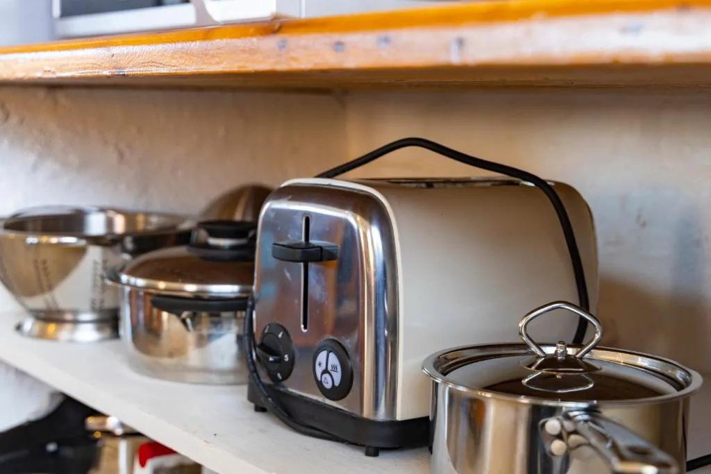 Stainless steel toaster and cookware on wooden kitchen shelf