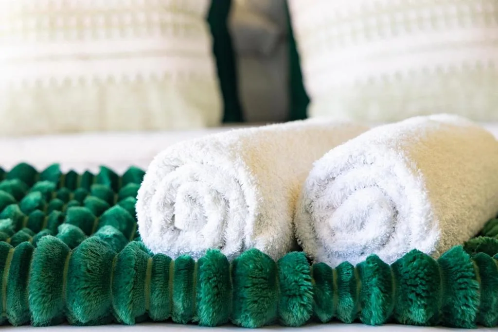 Rolled white and cream towels arranged on green bath mat