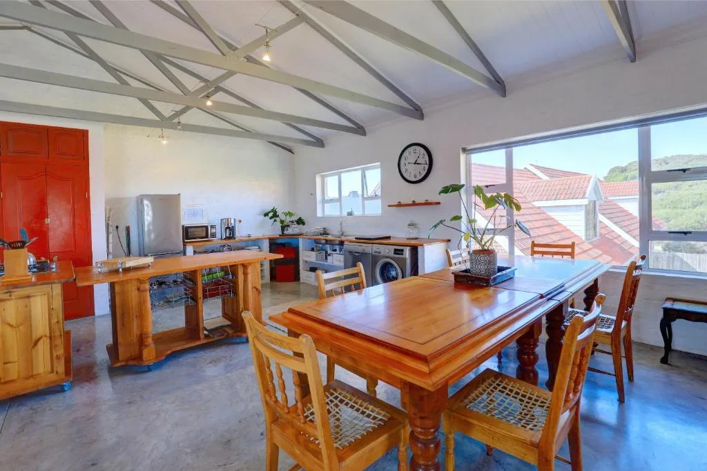 Spacious open-plan dining area with wooden table and chairs, kitchen beyond