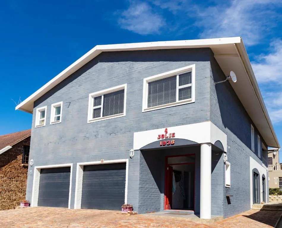 Modern two-story beach house with light blue brick facade and garage doors
