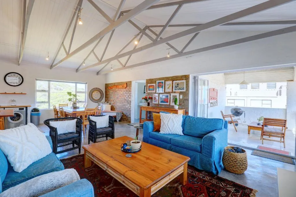 Bright open-plan lounge with blue sofas, wooden coffee table, and vaulted ceilings