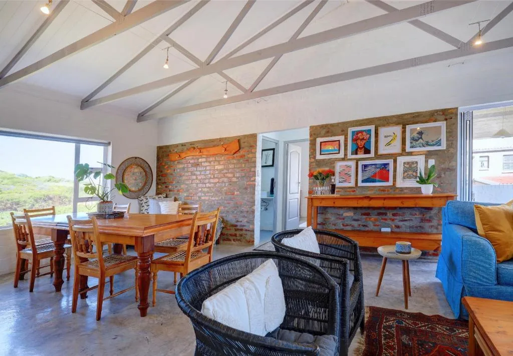 Open-plan lounge with blue sofa, woven chairs, exposed brick fireplace and artwork