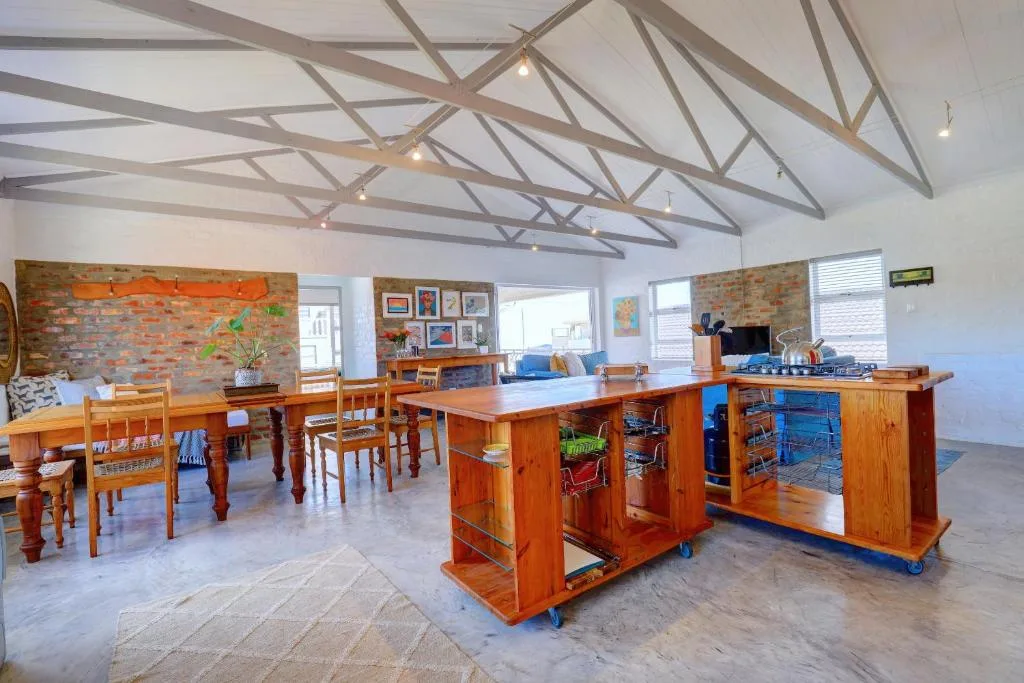 Open-plan lounge with wooden furniture, exposed brick wall, and vaulted ceiling