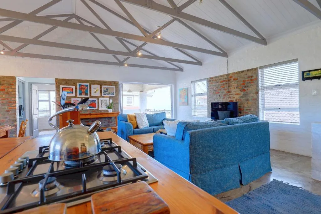 Open-plan lounge with blue sofas, exposed brick walls, and vaulted ceilings