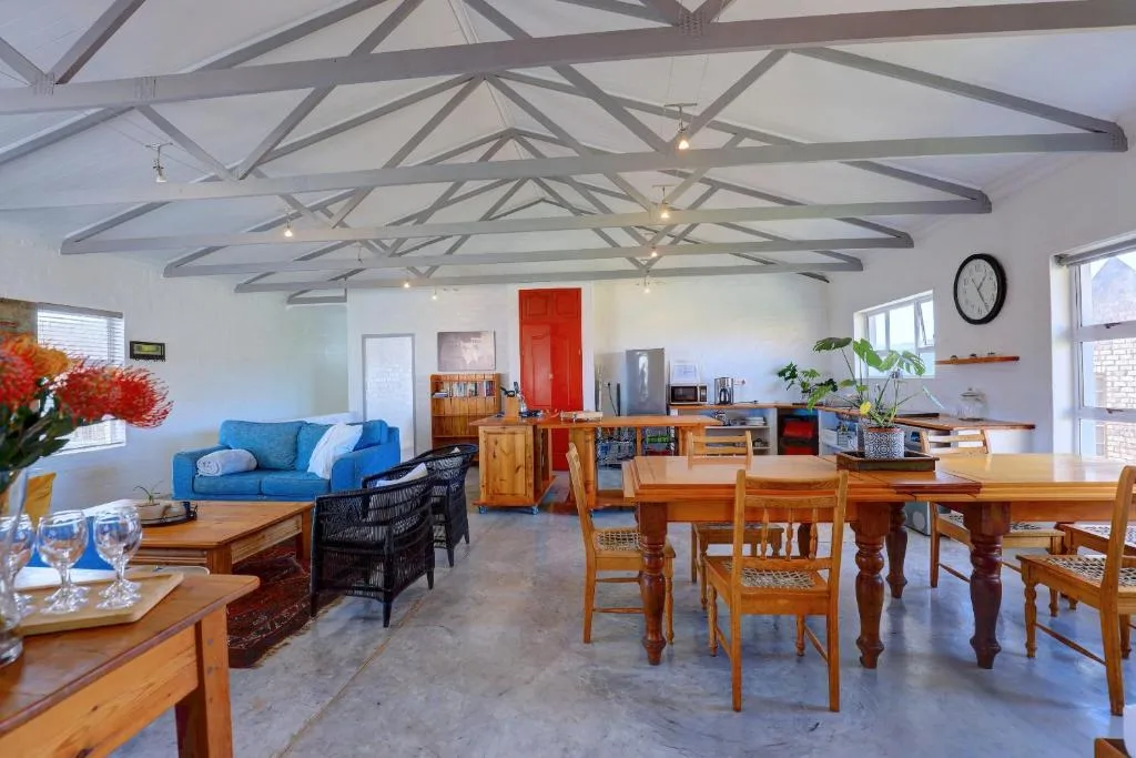 Open-plan lounge and dining area with blue sofa, wooden furniture, and exposed beams