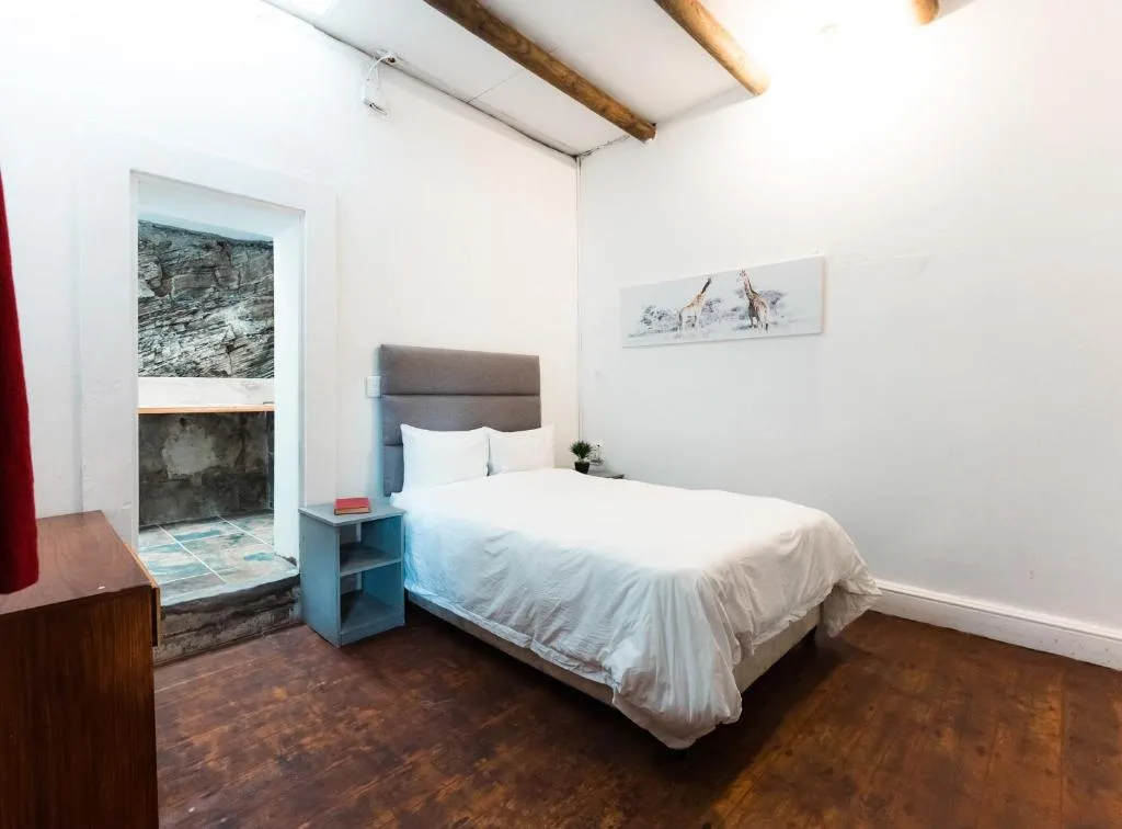 Spacious bedroom with bed, exposed wooden beams, and artistic wall decor