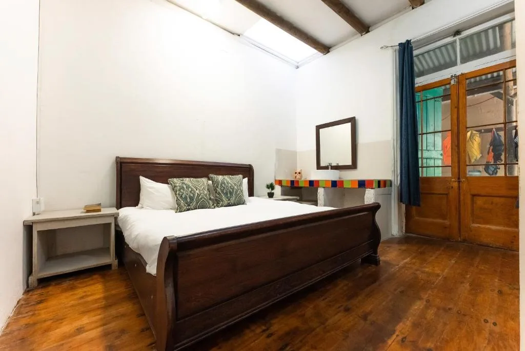 Spacious bedroom with dark wood bed frame and wooden flooring throughout