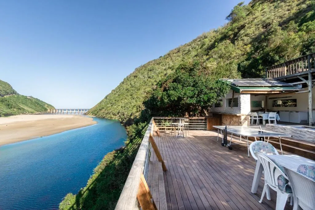 Wooden deck overlooking blue lagoon with white chairs and outdoor seating