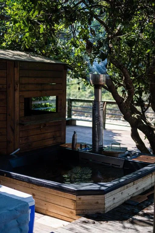 Wooden hot tub on shaded deck with mountain views and lush foliage