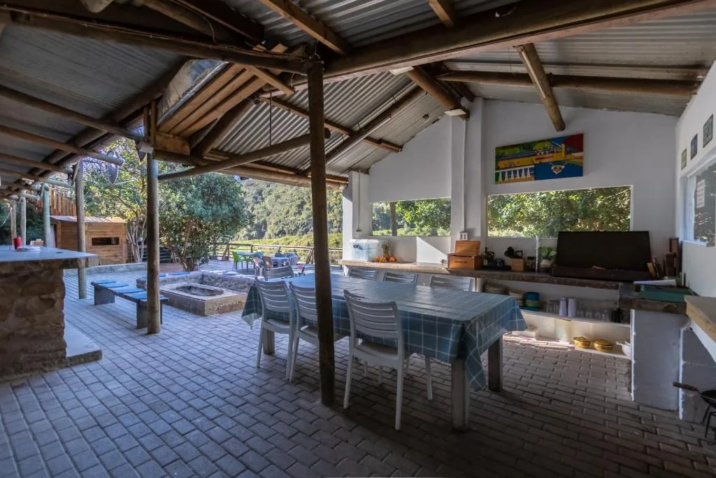 Covered outdoor deck with dining table, braai area, and garden views