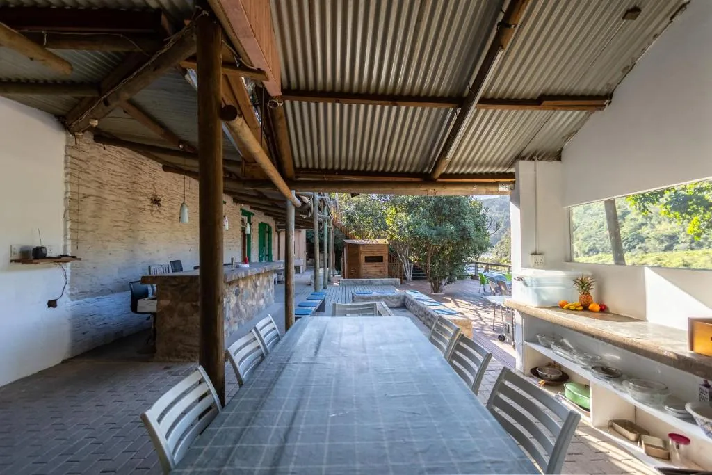 Covered outdoor dining area with long table and chairs, kitchen visible