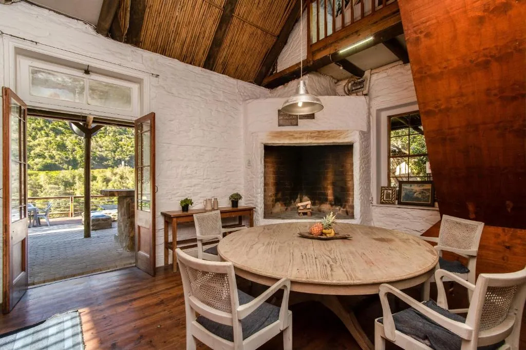 Spacious dining area with round wooden table and fireplace, open deck views