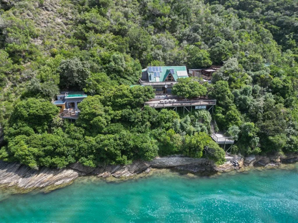 Waterfront property nestled among dense green forest with wooden deck overlooking turquoise water