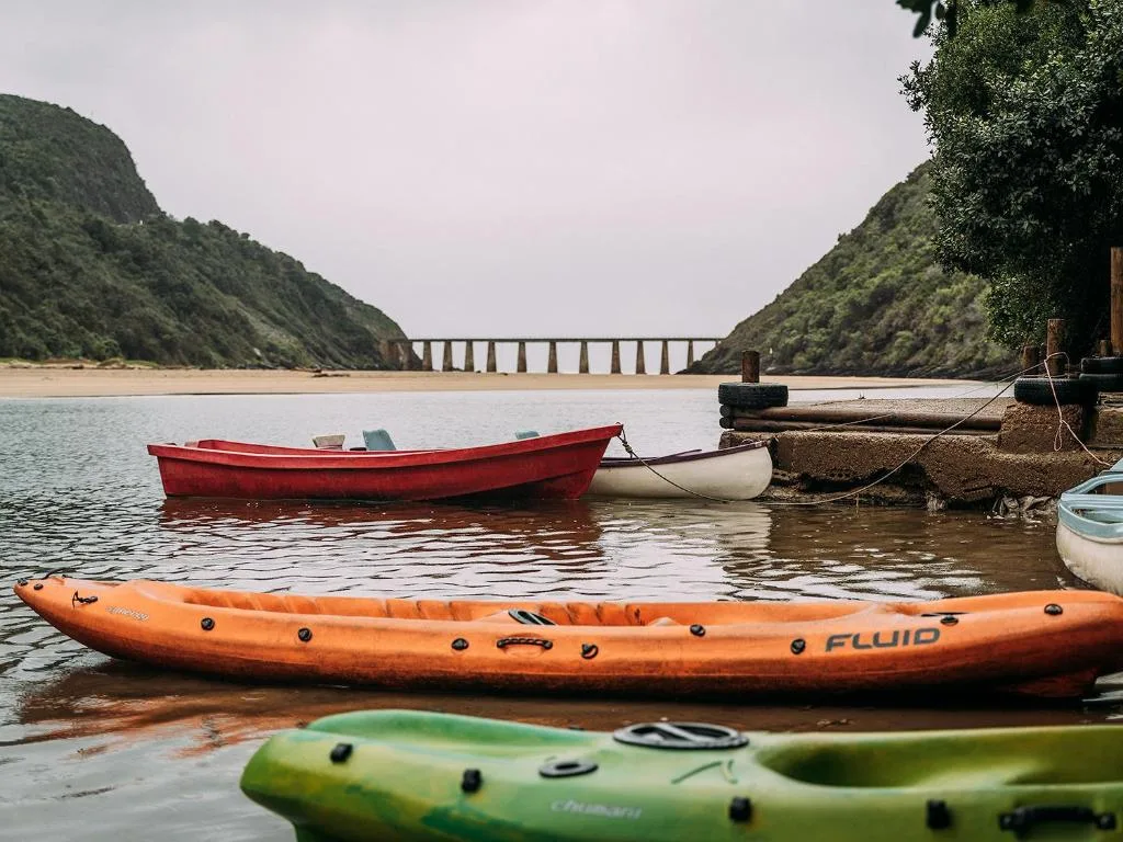 Scenic river valley with moored boats and bridge spanning lush green cliffs