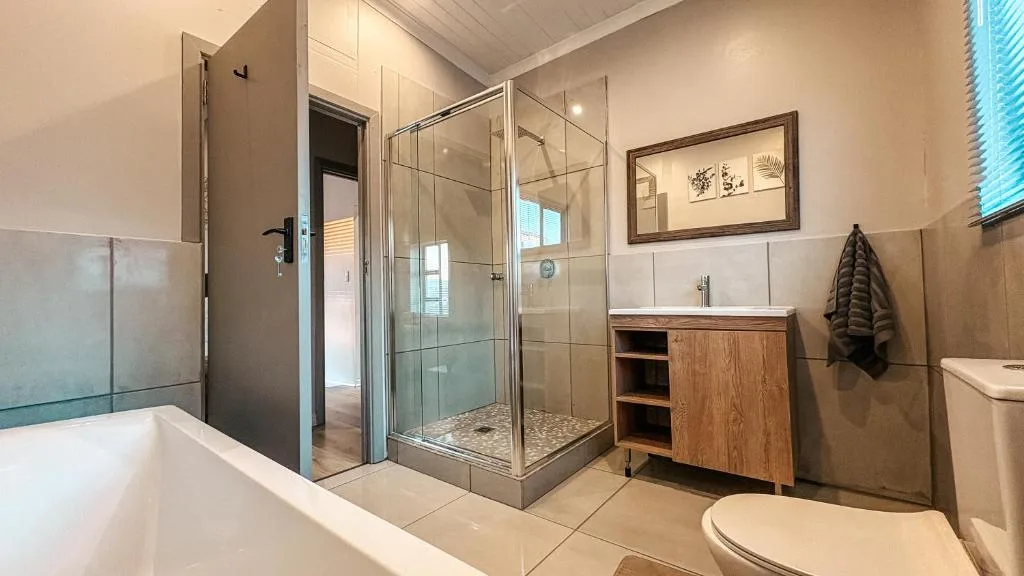 Modern bathroom with freestanding tub, glass shower enclosure, wooden vanity