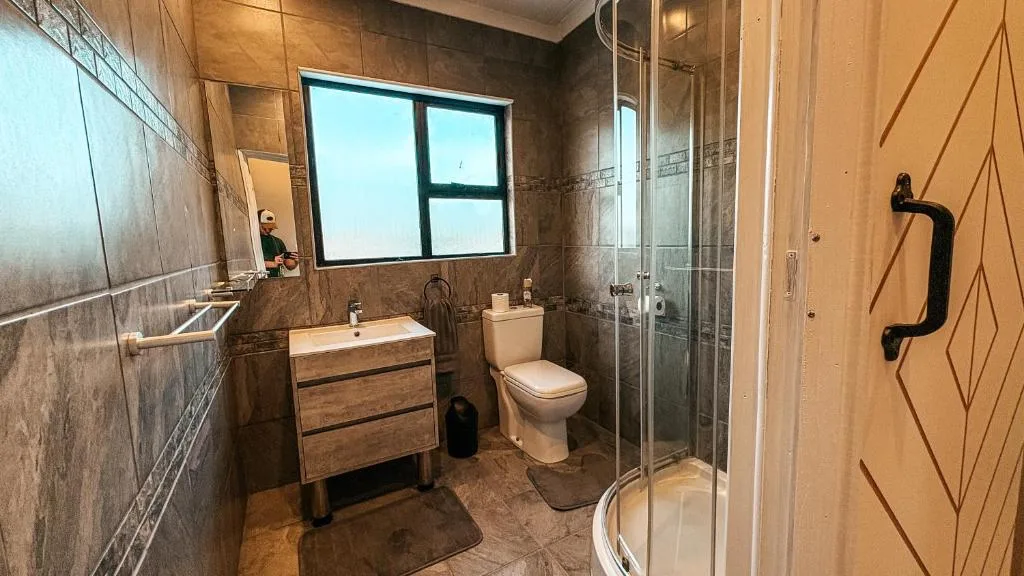 Modern bathroom with vanity, toilet, shower enclosure and window