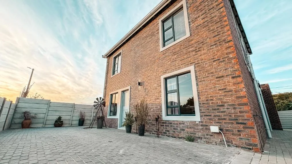 Modern brick home with paved patio and potted plants at dusk