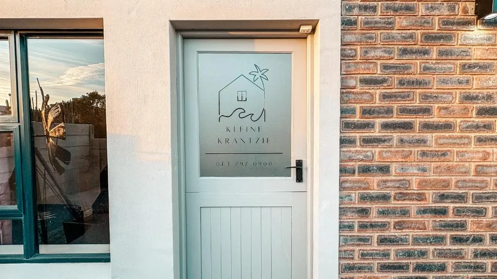 Light blue entrance door with property branding and contact details displayed