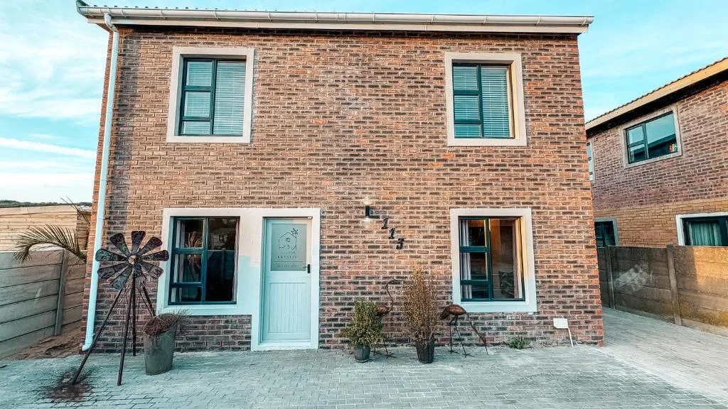 Modern brick holiday home facade with white door and potted plants entrance