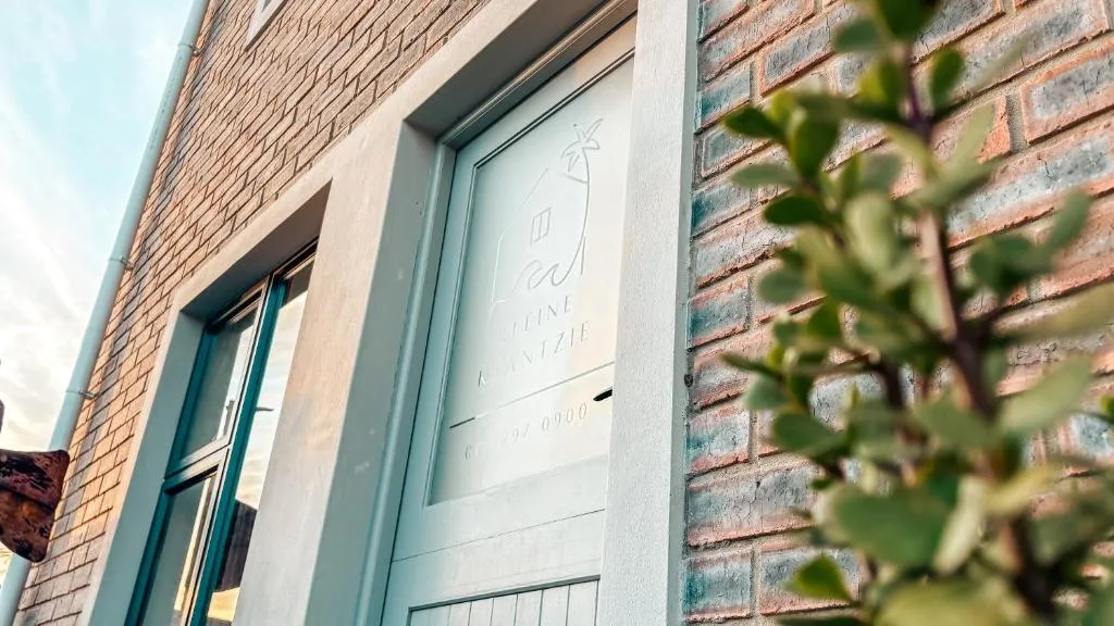 Modern light blue entrance door on brick building facade with greenery