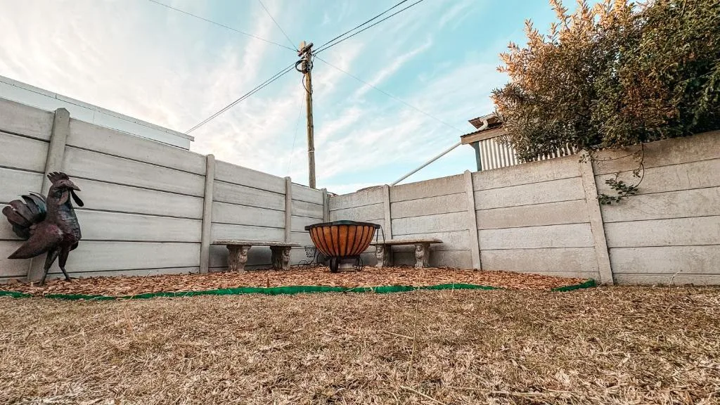 Fenced garden courtyard with fire bowl and metal rooster sculpture