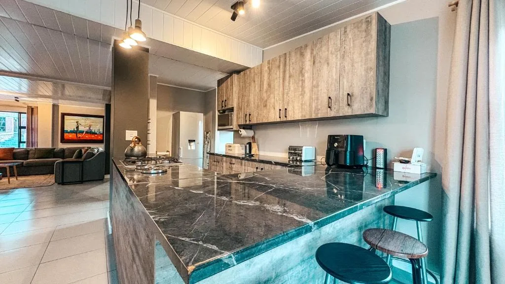 Modern kitchen with dark marble countertop, wooden cabinetry, and bar seating