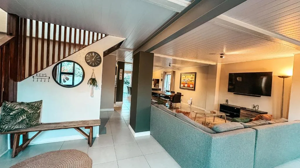 Modern open-plan lounge with turquoise sofa, wall-mounted TV, and wooden accents