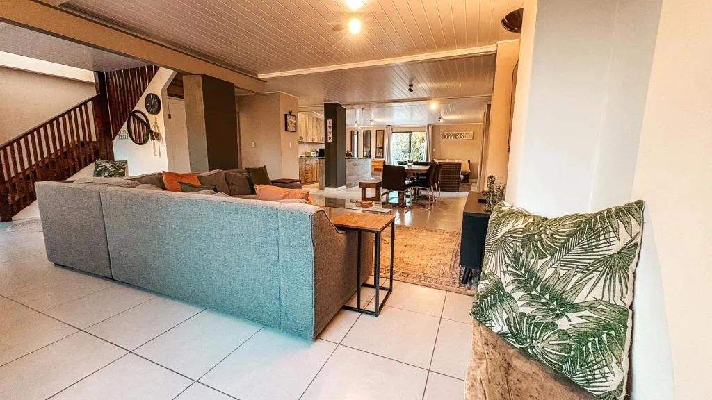 Open-plan lounge with turquoise sofa, wooden ceiling, and staircase access