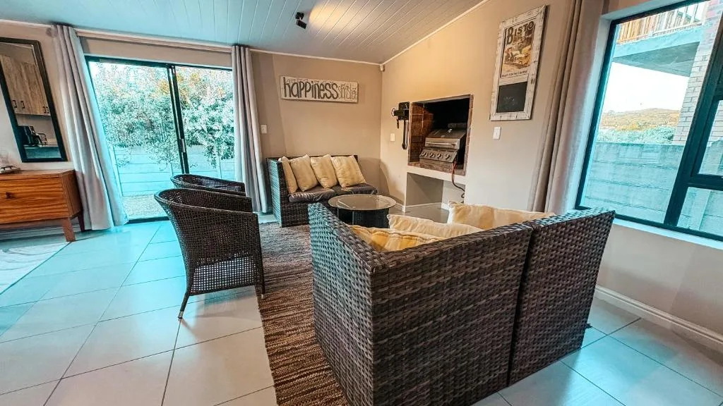 Open-plan lounge with rattan seating, fireplace, and deck access overlooking water