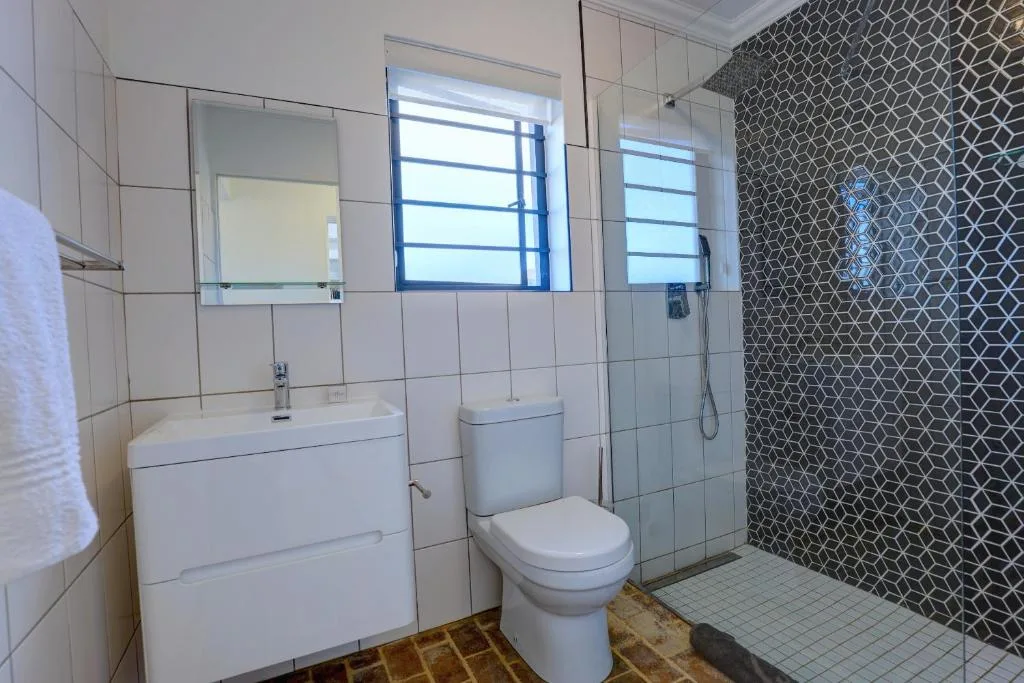 Modern bathroom with vanity, toilet, patterned tile shower enclosure