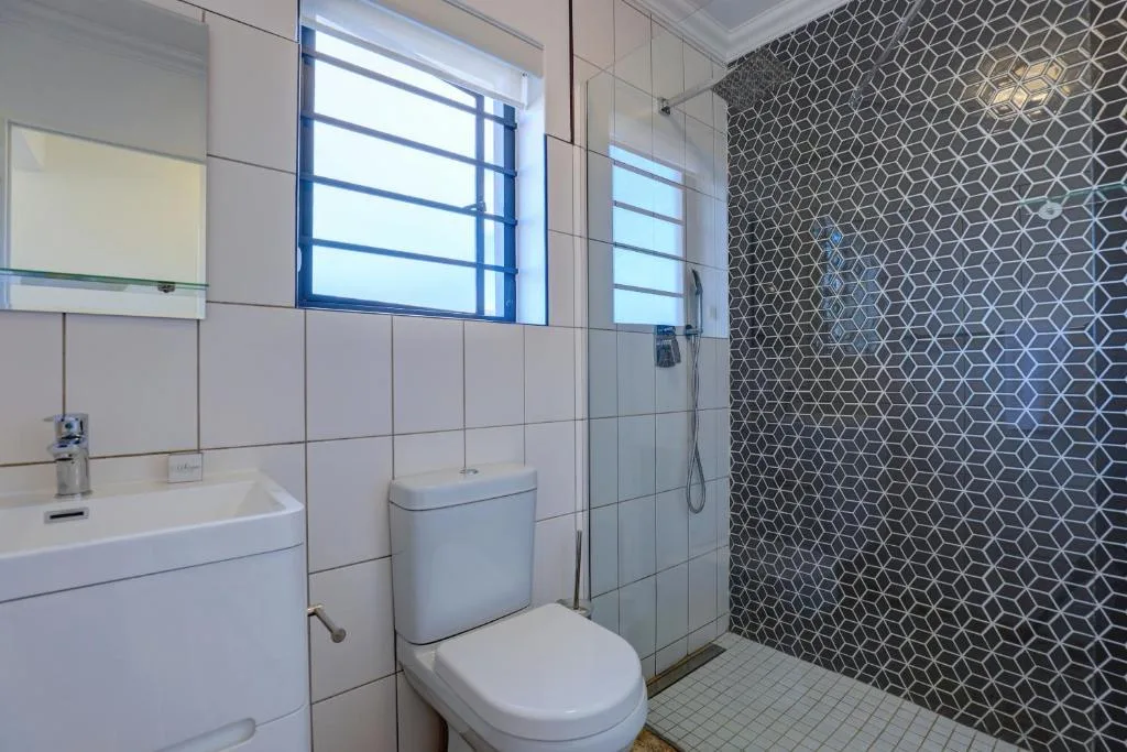 Modern bathroom with geometric tile shower wall and natural light window