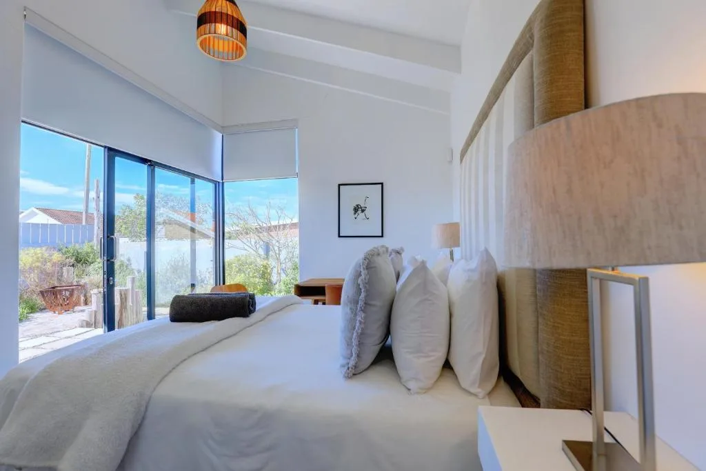 Bright bedroom with large windows overlooking garden and deck area