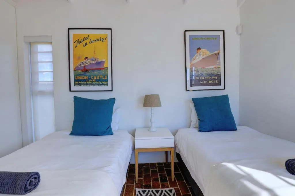 Twin bedroom with white beds, blue pillows, vintage ship posters