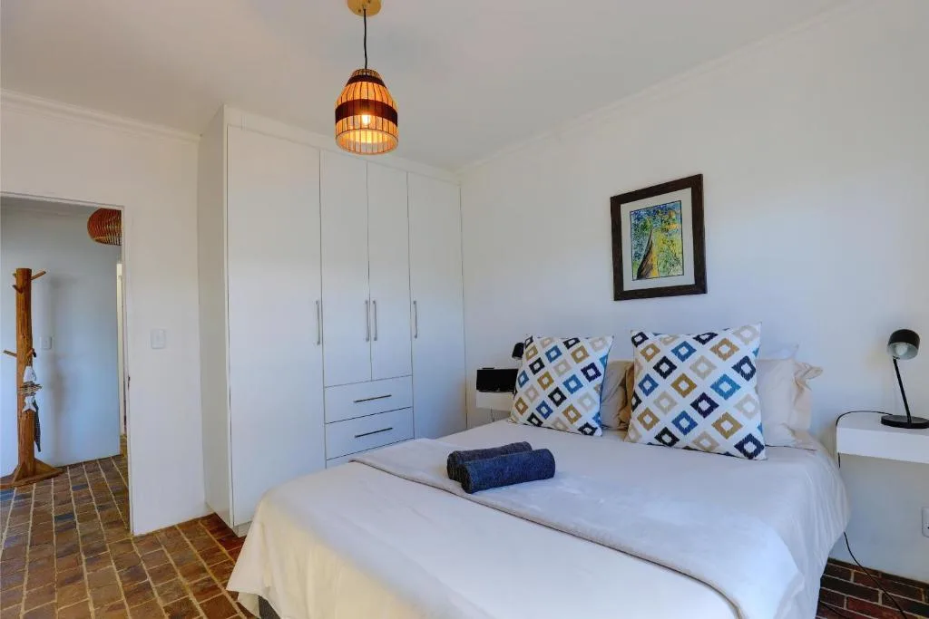 Bright bedroom with white bed, patterned pillows, and modern wardrobe storage