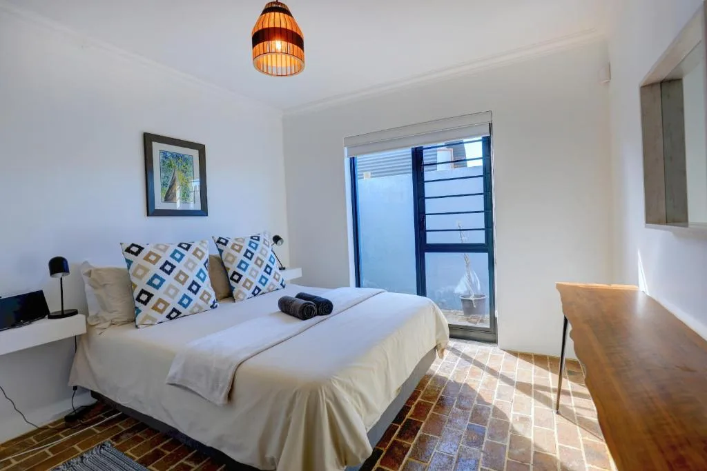 Bright bedroom with queen bed, patterned pillows, and access to deck