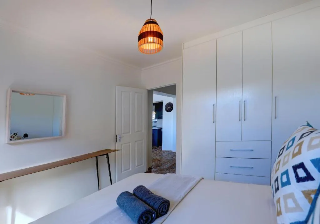 Bright bedroom with white built-in wardrobes and pendant light fixture