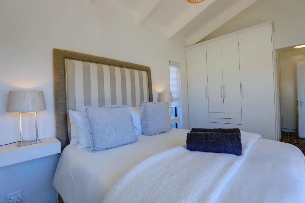 Bright bedroom with double bed, striped headboard, white wardrobe and bedside lamp