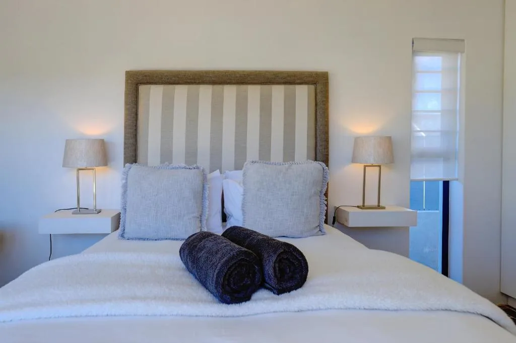 Spacious bedroom with striped upholstered headboard and crisp white bedding