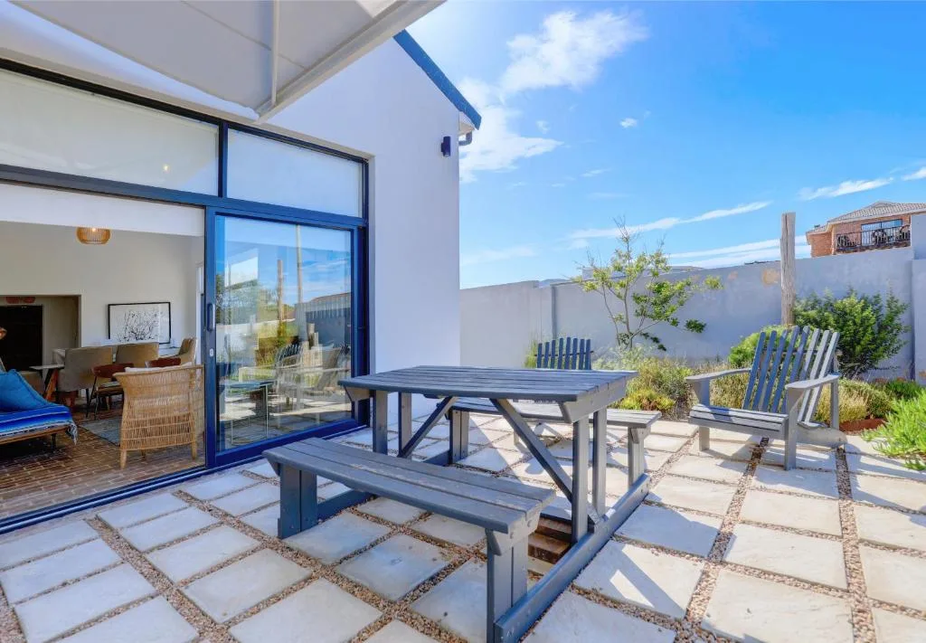 Spacious patio with picnic table and Adirondack chairs overlooking garden