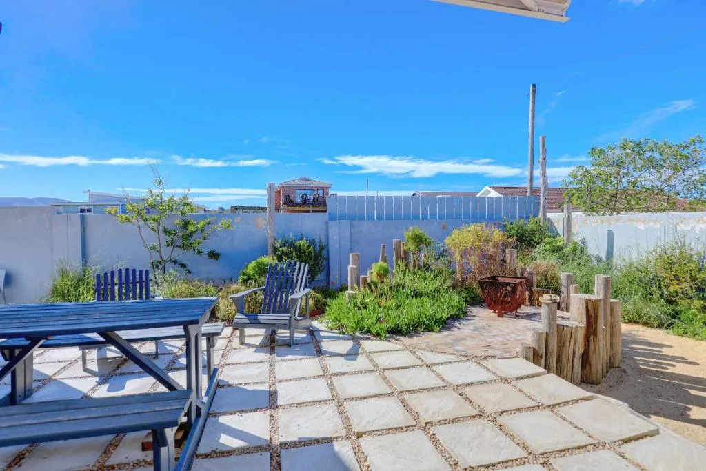 Outdoor patio with blue seating, stone paving, and lush garden plantings